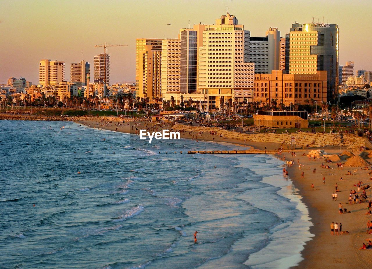 Scenic view of sea and buildings against sky during sunset