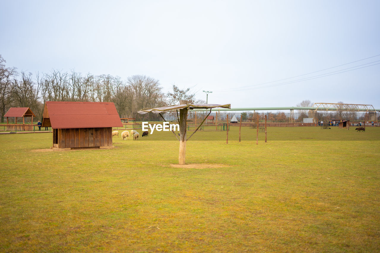 architecture, rural area, grass, sky, built structure, plant, nature, building exterior, building, house, tree, landscape, land, farm, field, day, no people, environment, residential district, outdoors, plain, pasture, meadow, playground