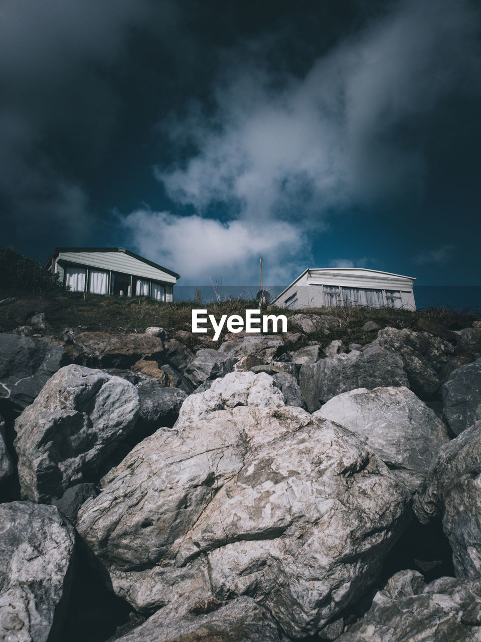 Low angle view of building on rock against sky