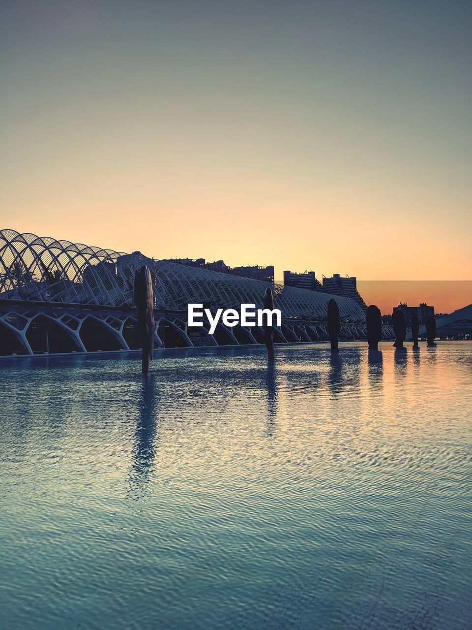 BRIDGE OVER RIVER AGAINST SKY DURING SUNSET