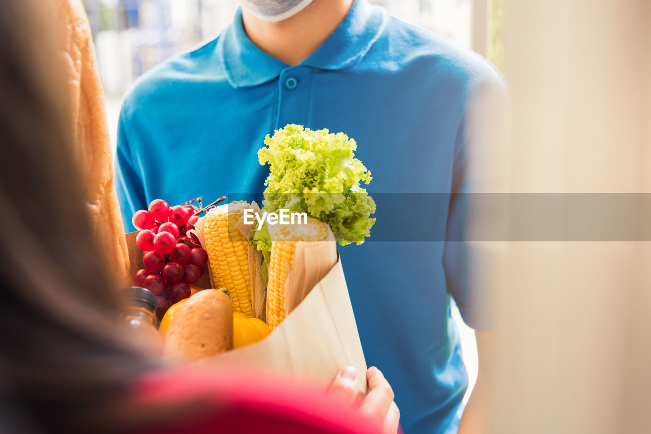 Asian young delivery man in uniform wear protective face mask he making grocery