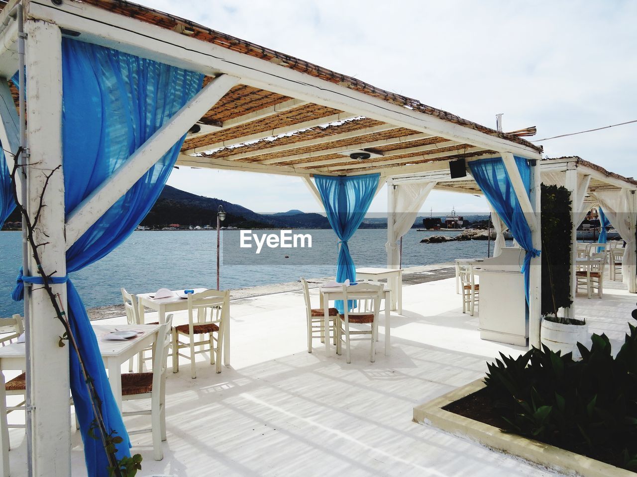 Empty chairs and tables by the sea