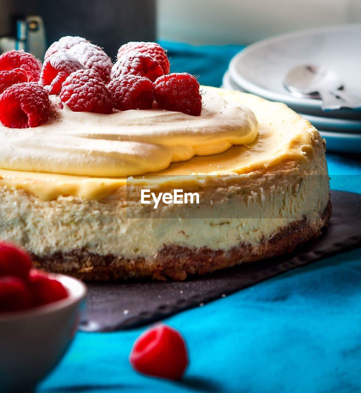 Cheesecake garnished with raspberries on table