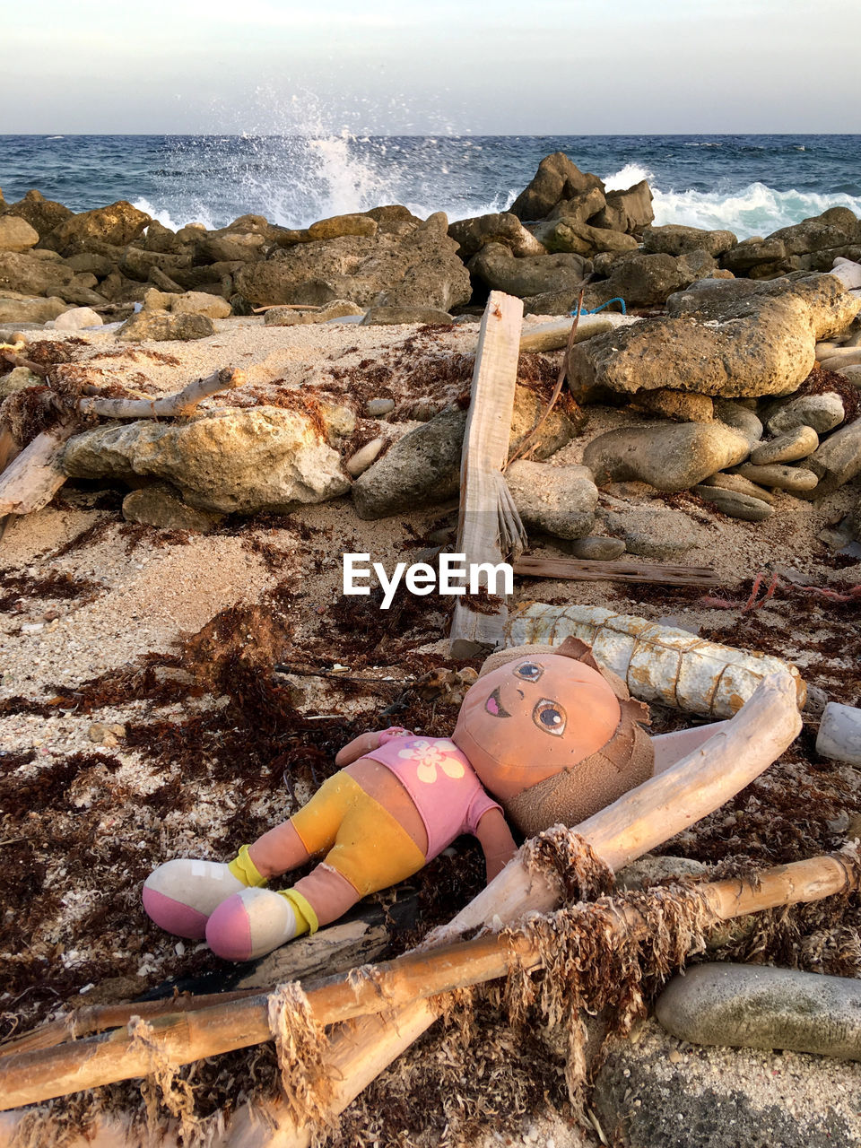 Portrait of doll lying on rock by sea shore