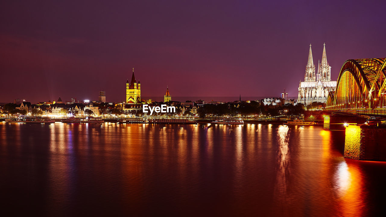 Illuminated hohenzollern bridge over rhine river with reflection at night