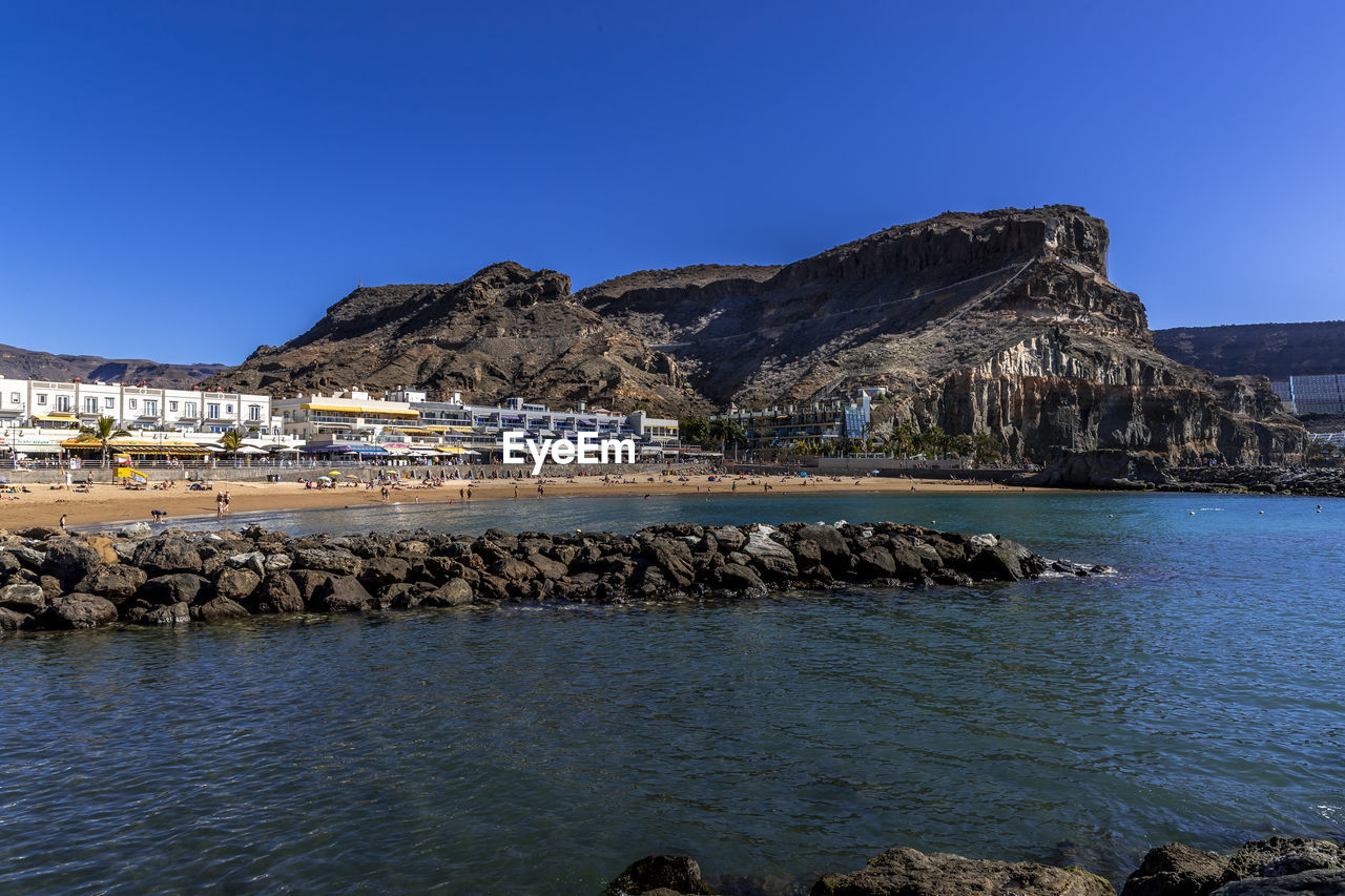 SCENIC VIEW OF SEA BY ROCK AGAINST CLEAR BLUE SKY