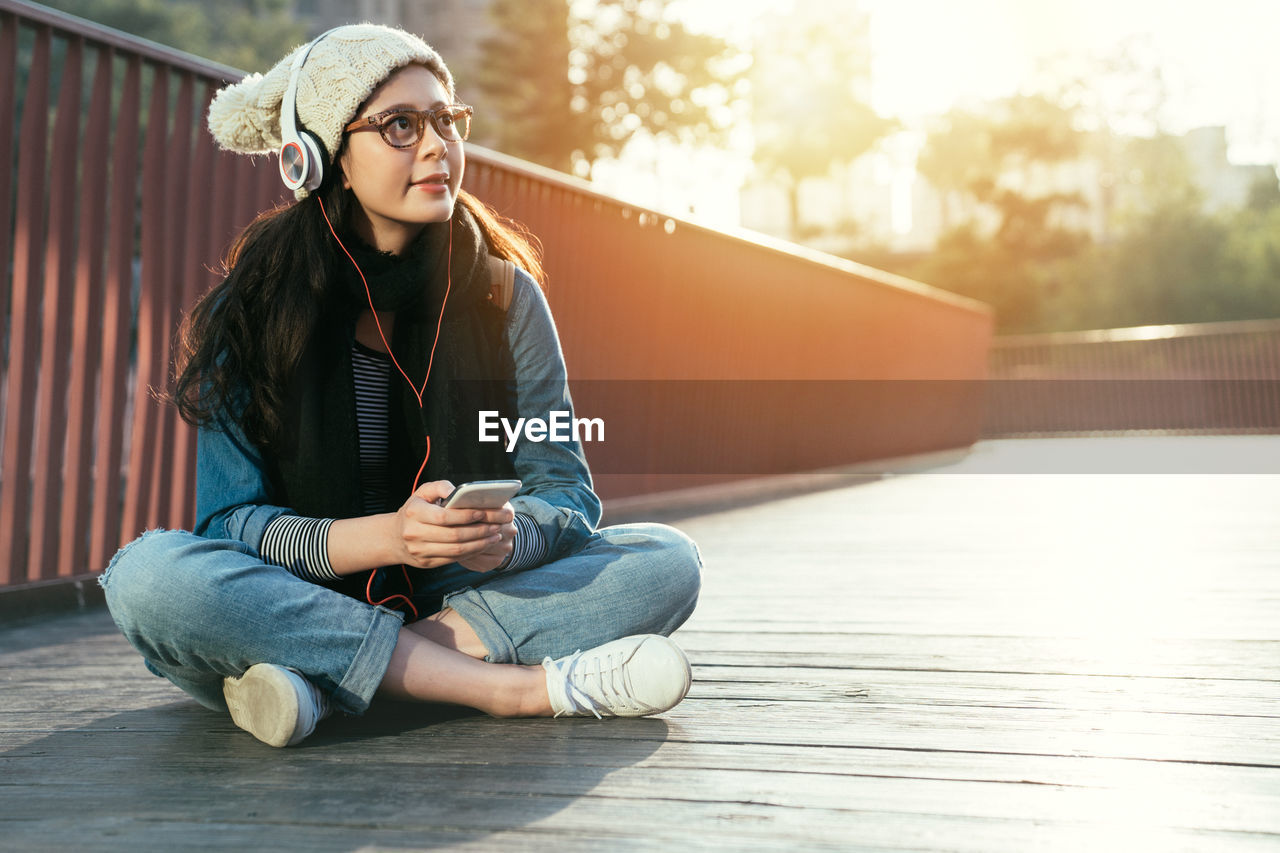 Close-up of young woman listening to music on footpath