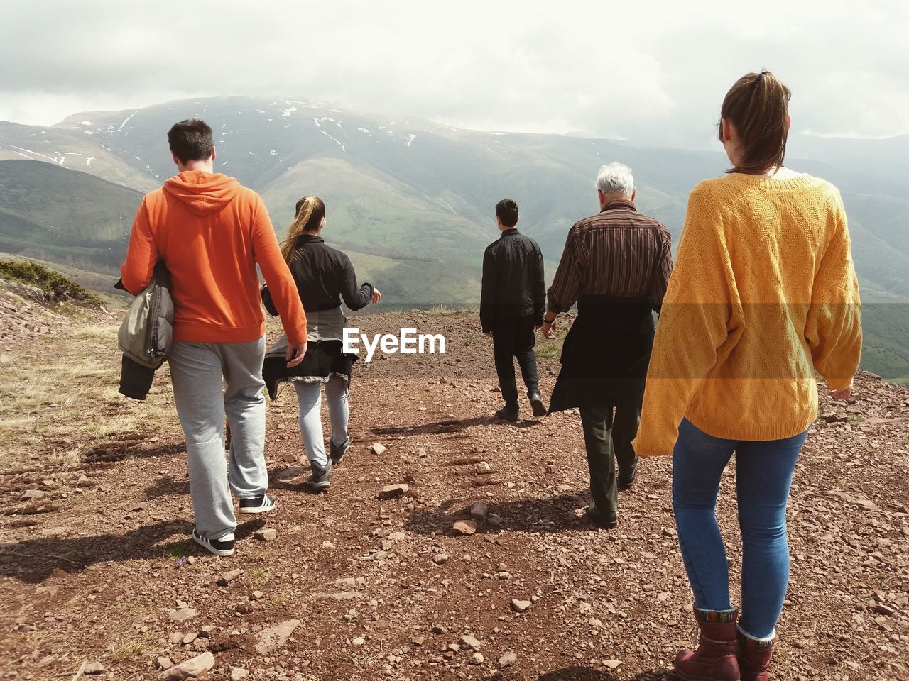Rear view of people walking on mountain against sky