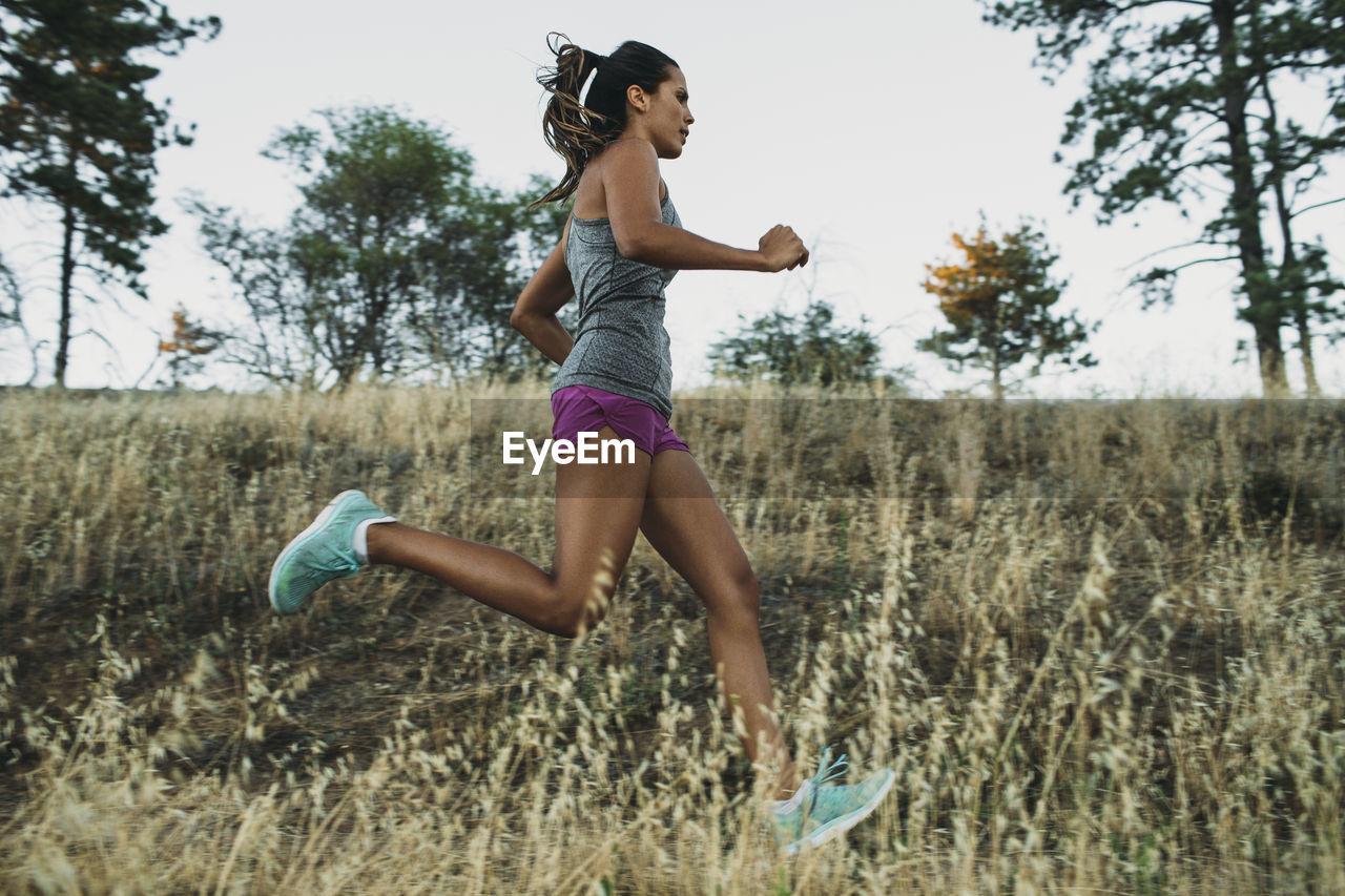 Low angle view of sportswoman running on grassy field