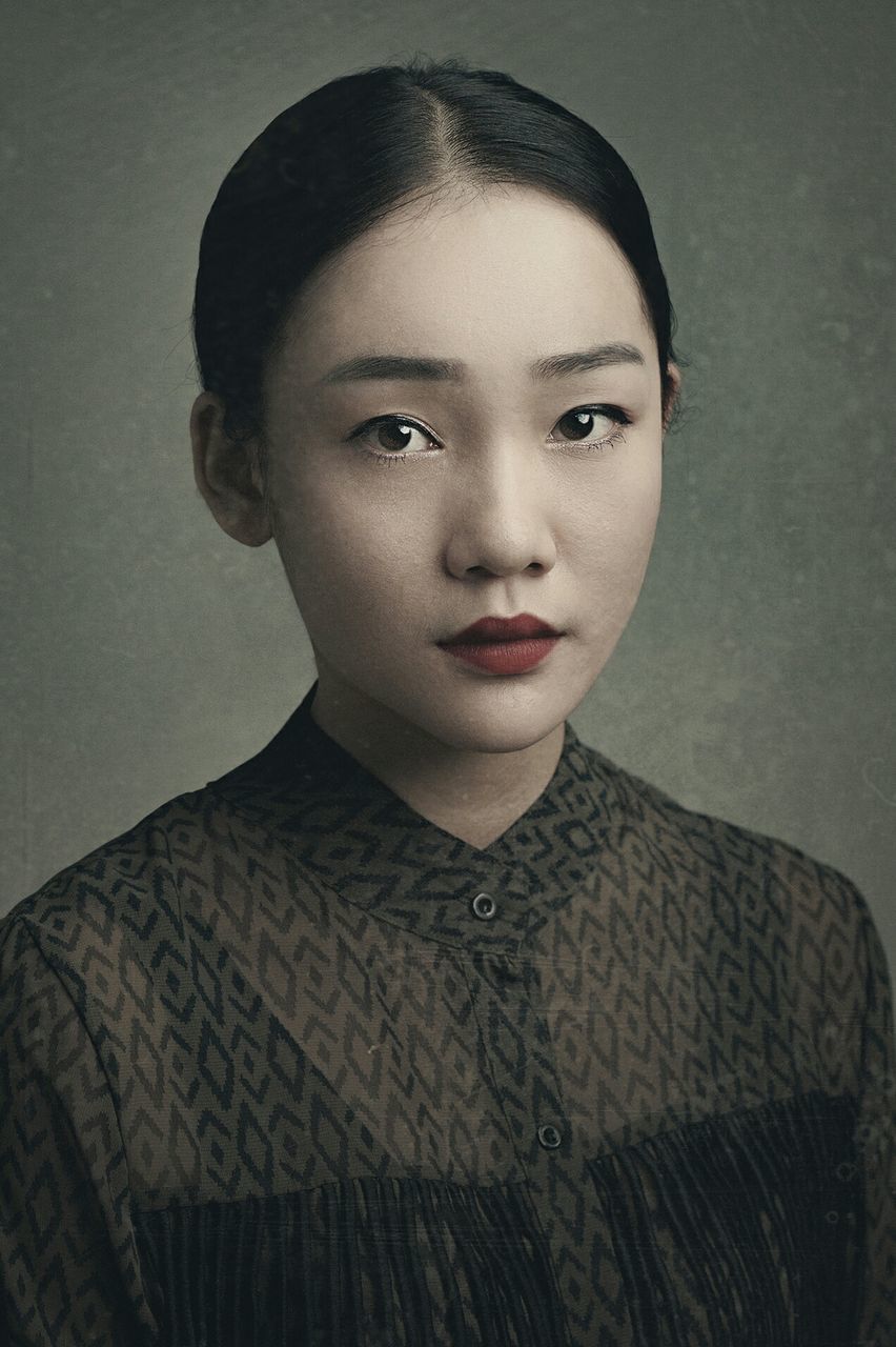 CLOSE-UP PORTRAIT OF BEAUTIFUL YOUNG WOMAN OVER GRAY BACKGROUND