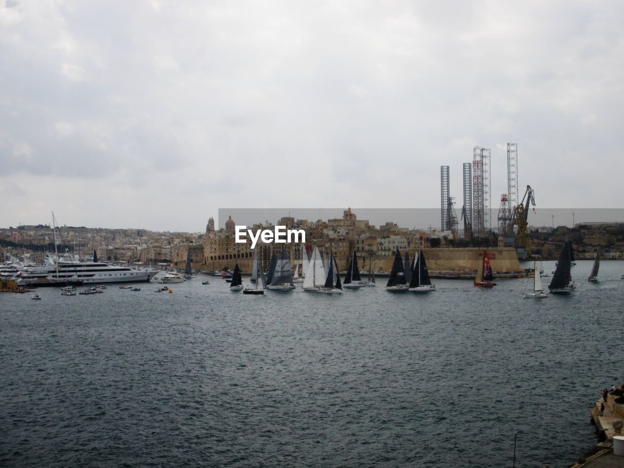 Sailboats in sea against buildings in city