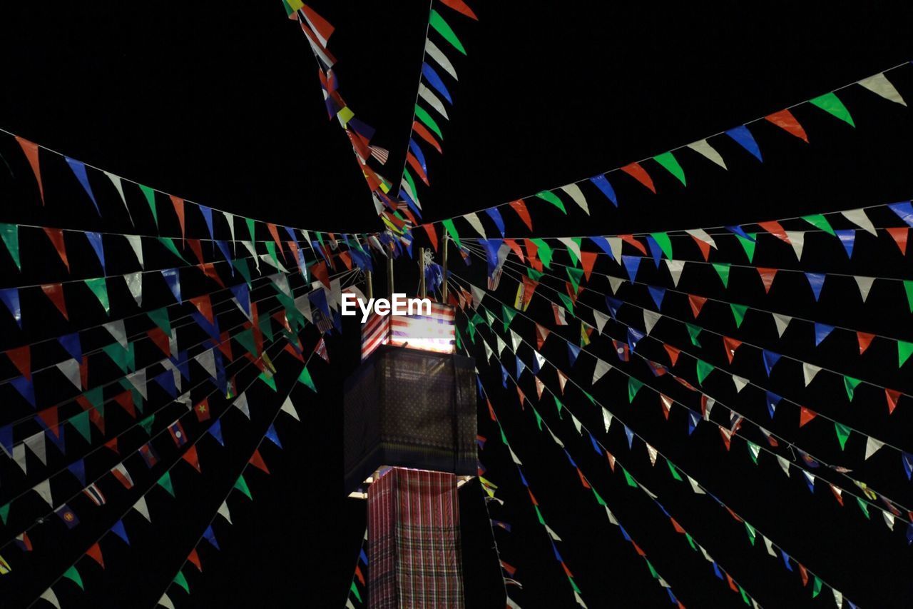 Low angle view of illuminated flags hanging at night