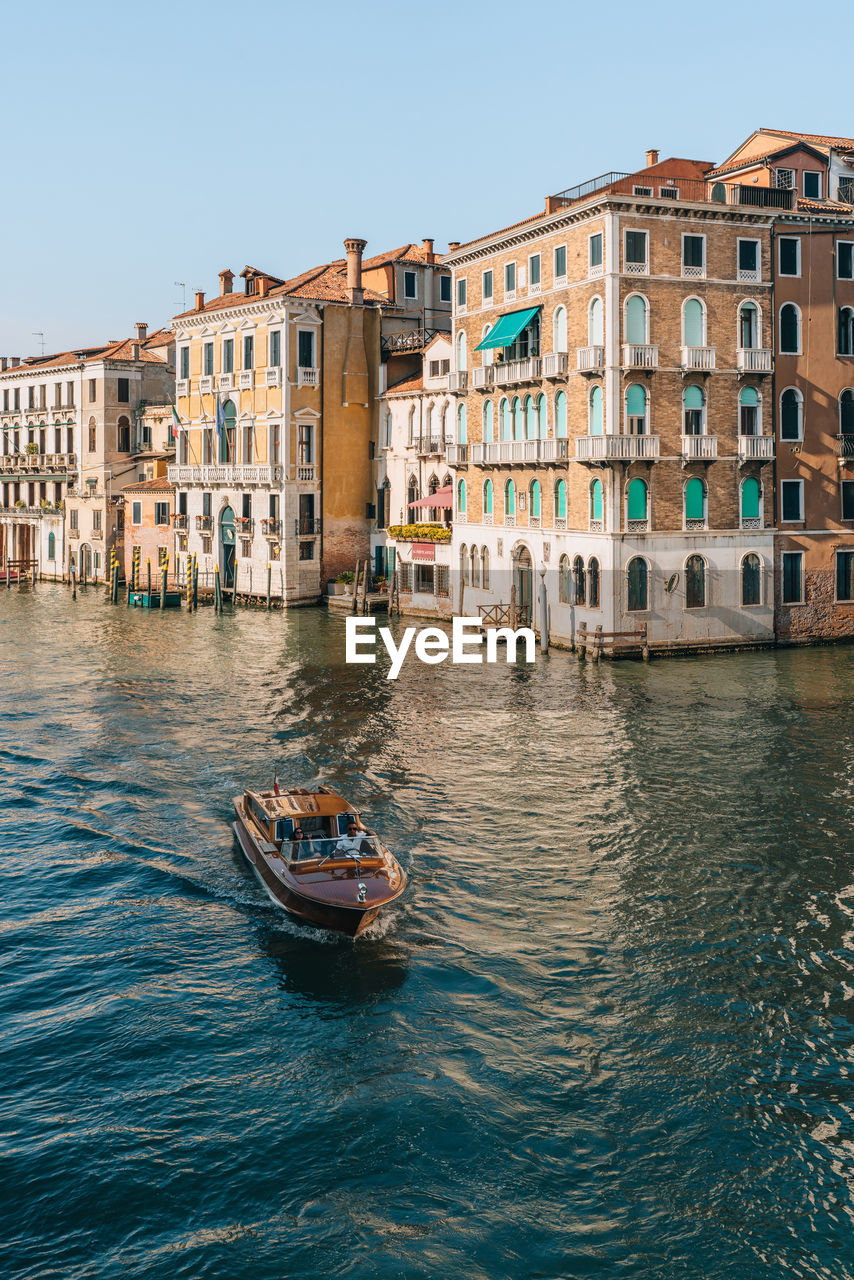 Water taxi navigating through grand canal and the buildings from rialto bridge in venice, italy.