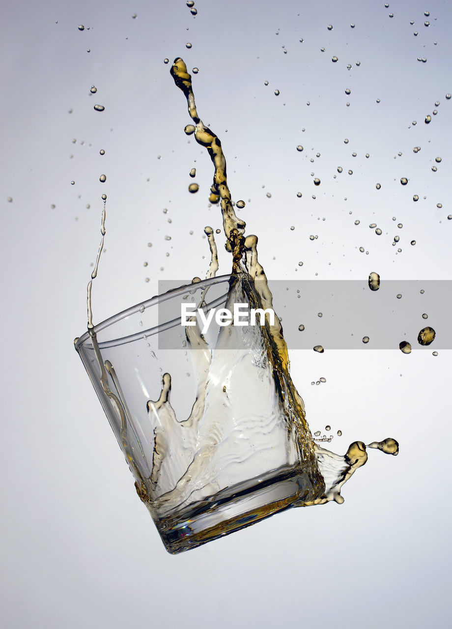 Close-up of glass with splashing whiskey against gray background
