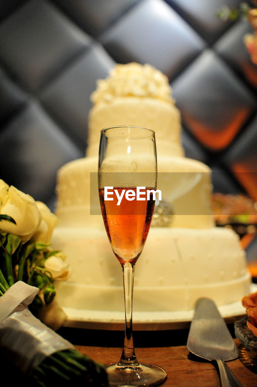 Close-up of drink in champagne flute by cake at table