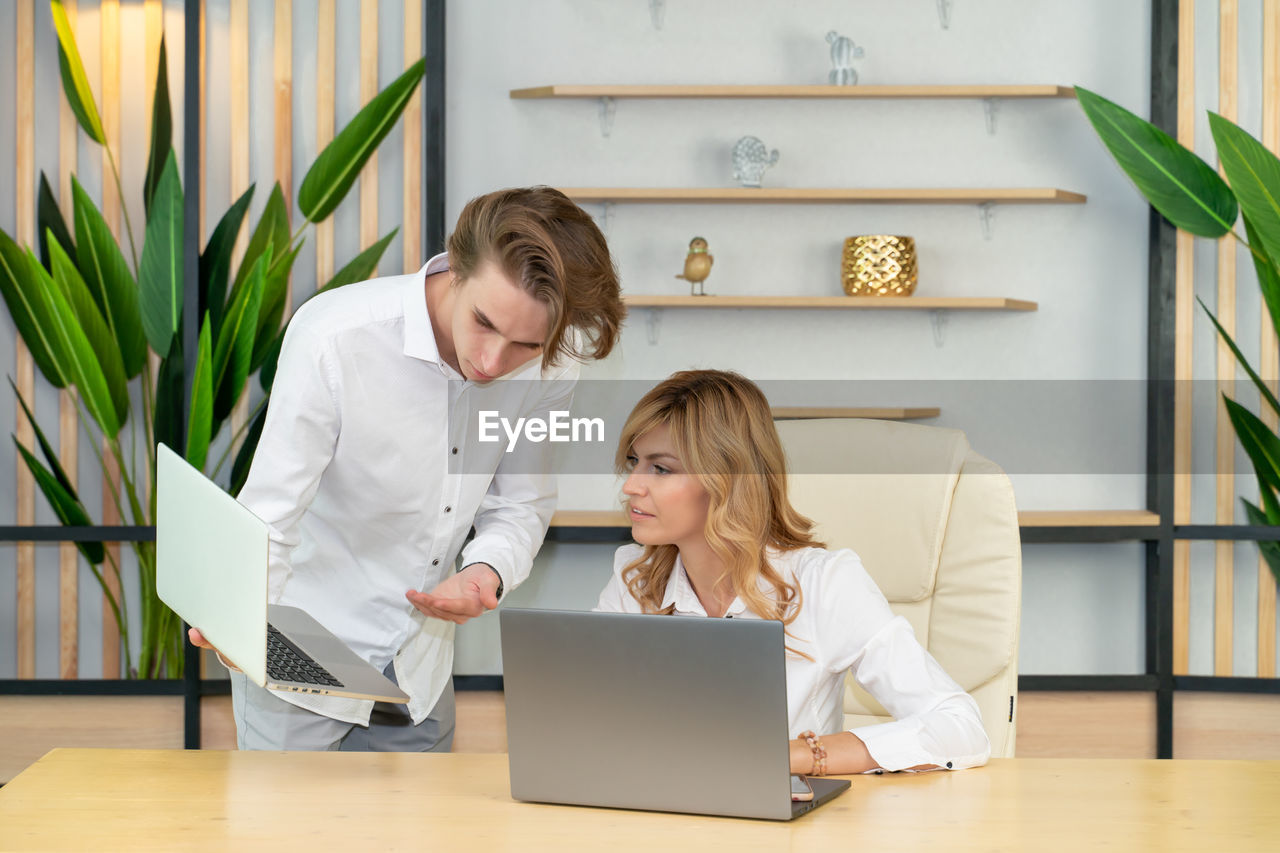 Business team using laptop in office showing collaboration, support, unity, partnership, motivation