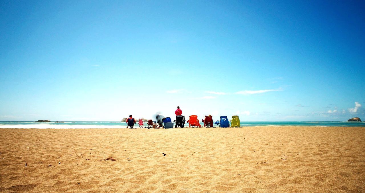 TOURISTS ON BEACH AGAINST CLEAR SKY