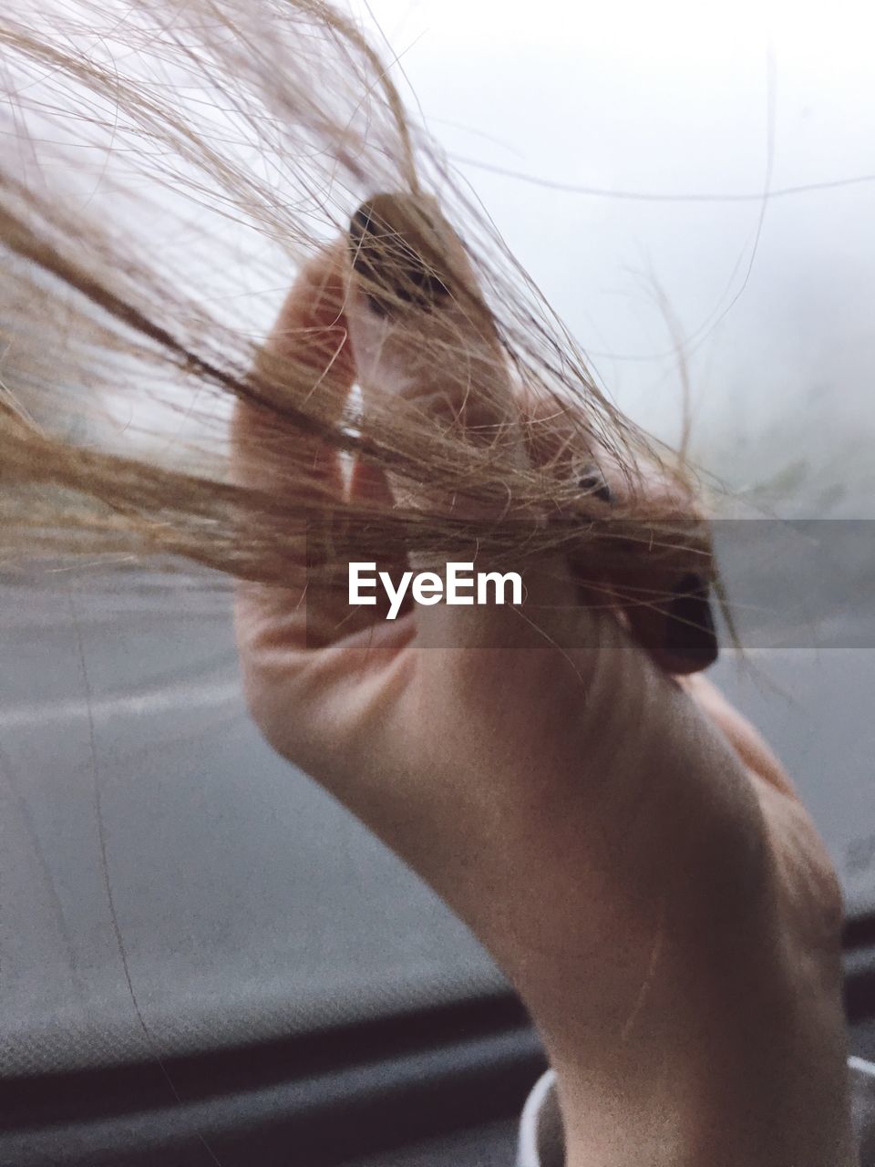 Cropped hand of woman holding hair in car