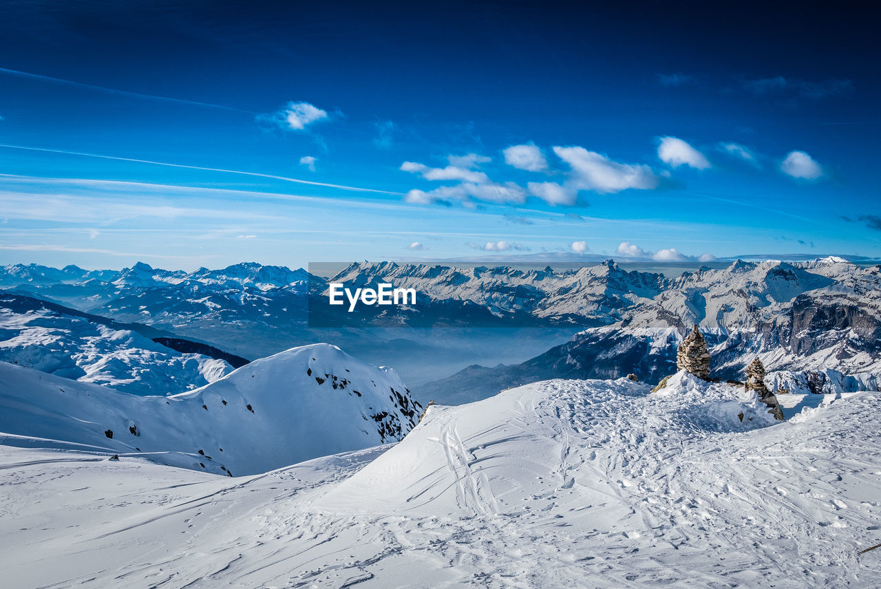 Scenic view of snowcapped mountains against blue sky