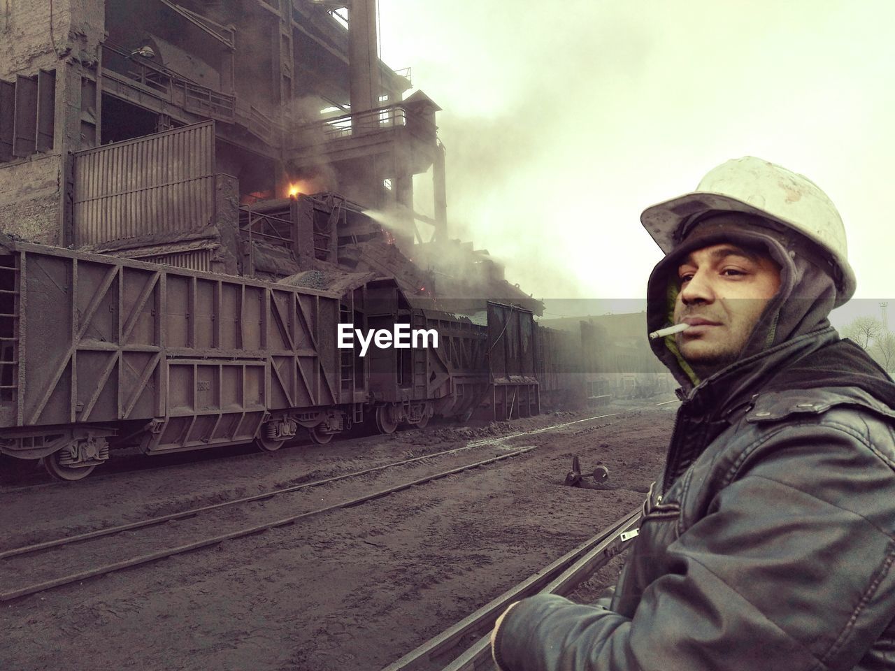 Worker smoking cigarette by railroad tracks