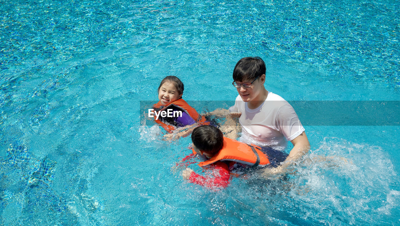 Father with kids playing in swimming pool