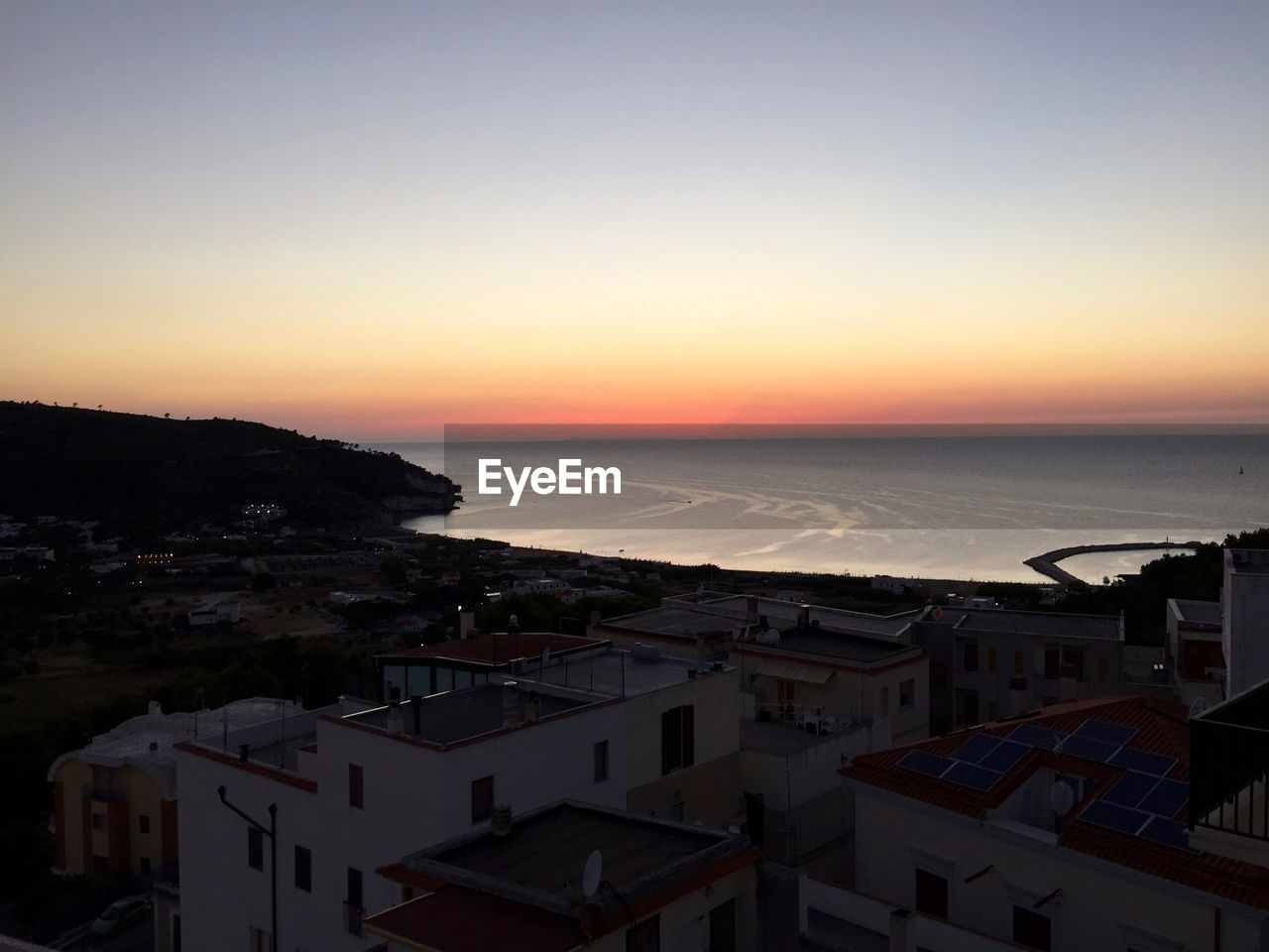 HIGH ANGLE SHOT OF TOWNSCAPE BY SEA AGAINST SKY