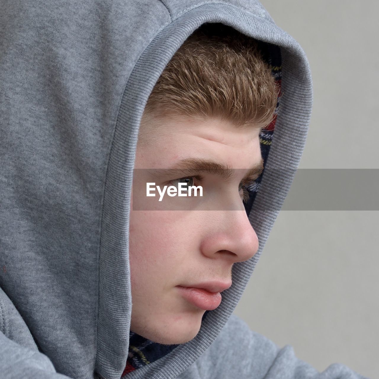 Close-up of thoughtful man in gray hooded shirt looking away