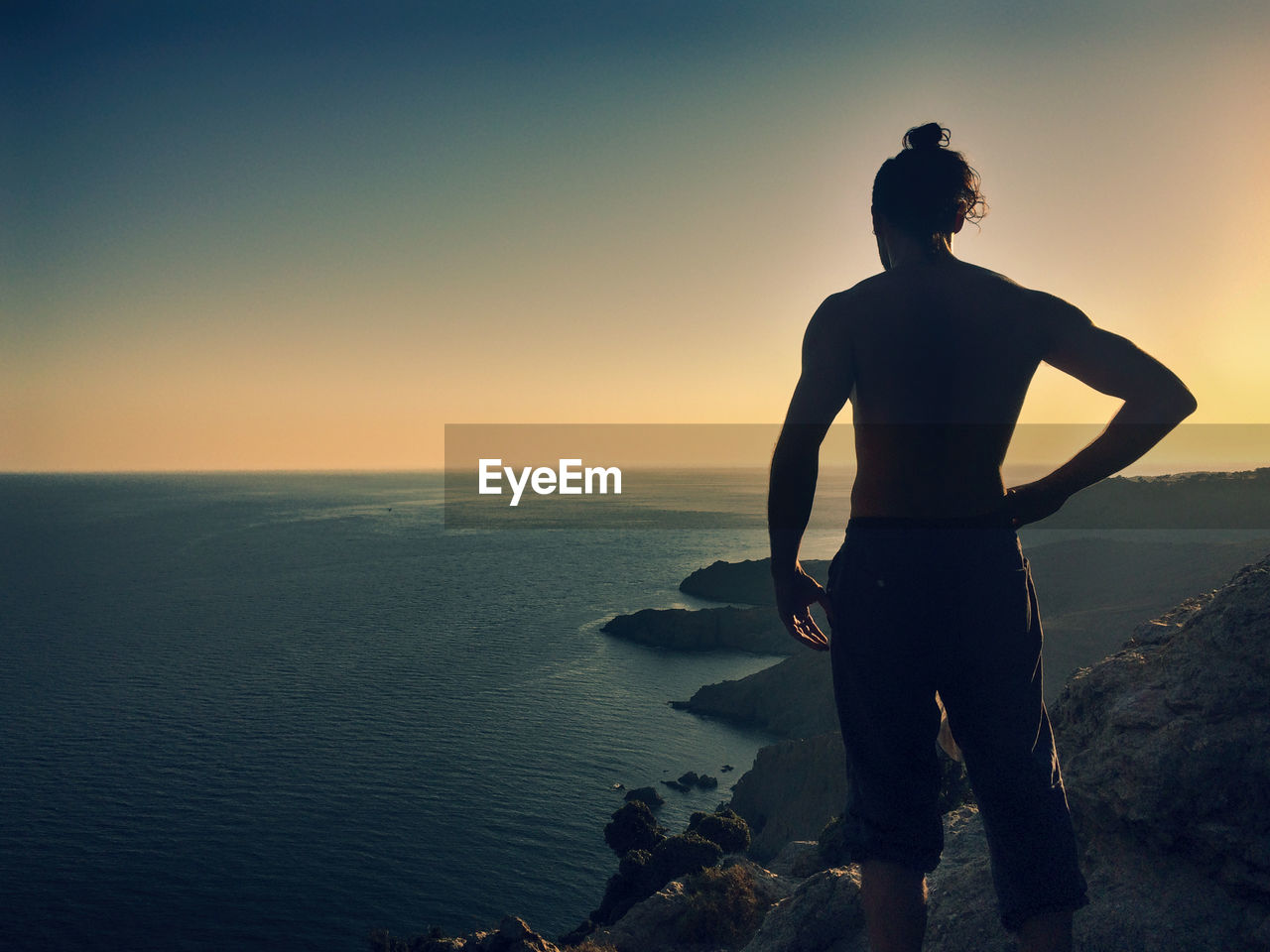 Rear view of man standing on rock against sea