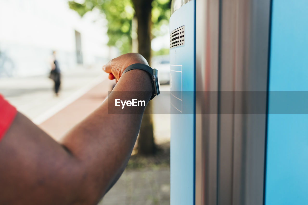 Hand of woman with smart watch using tap to pay method at ticket machine