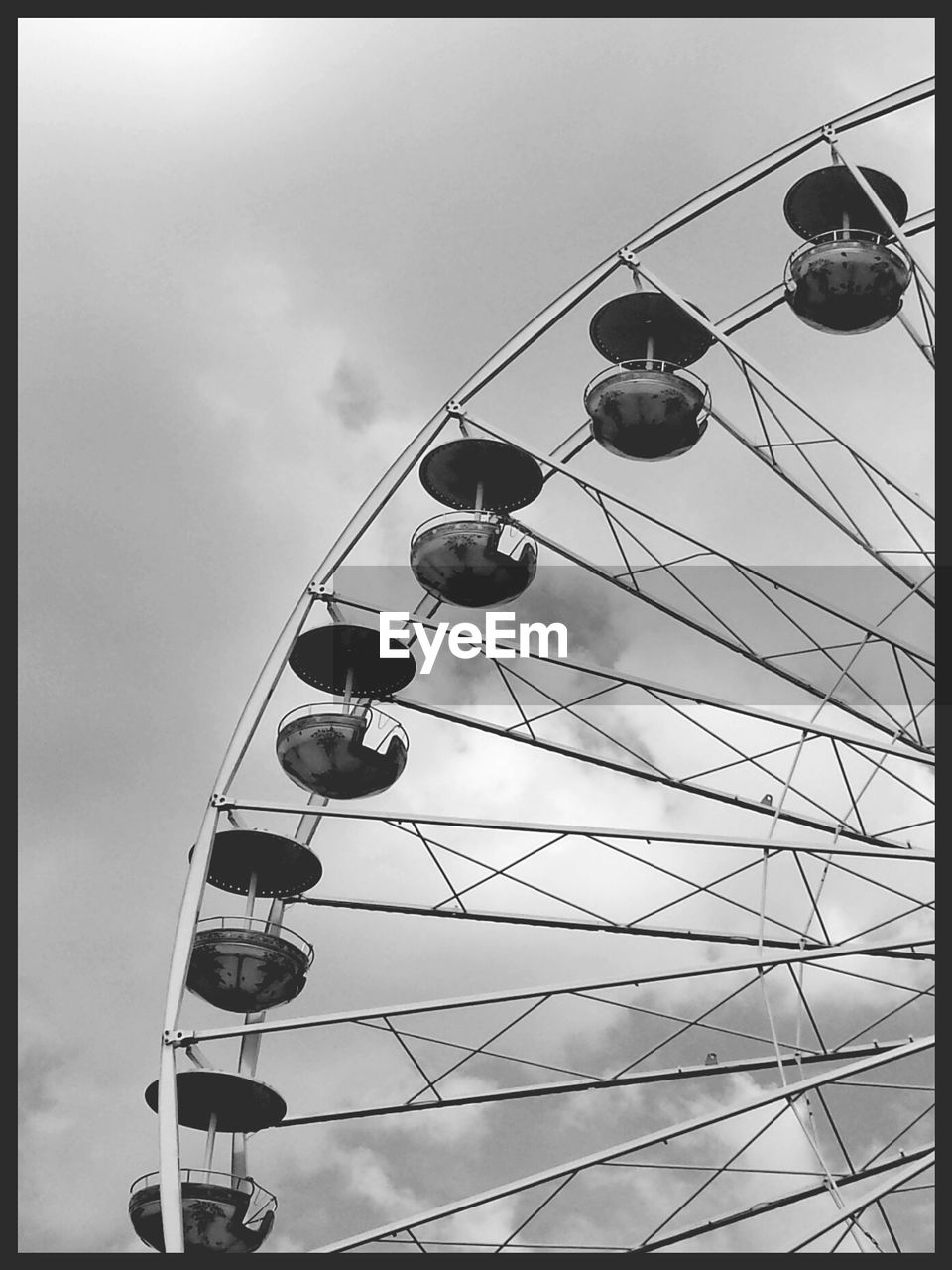 Low angle view of ferris wheel against cloudy sky