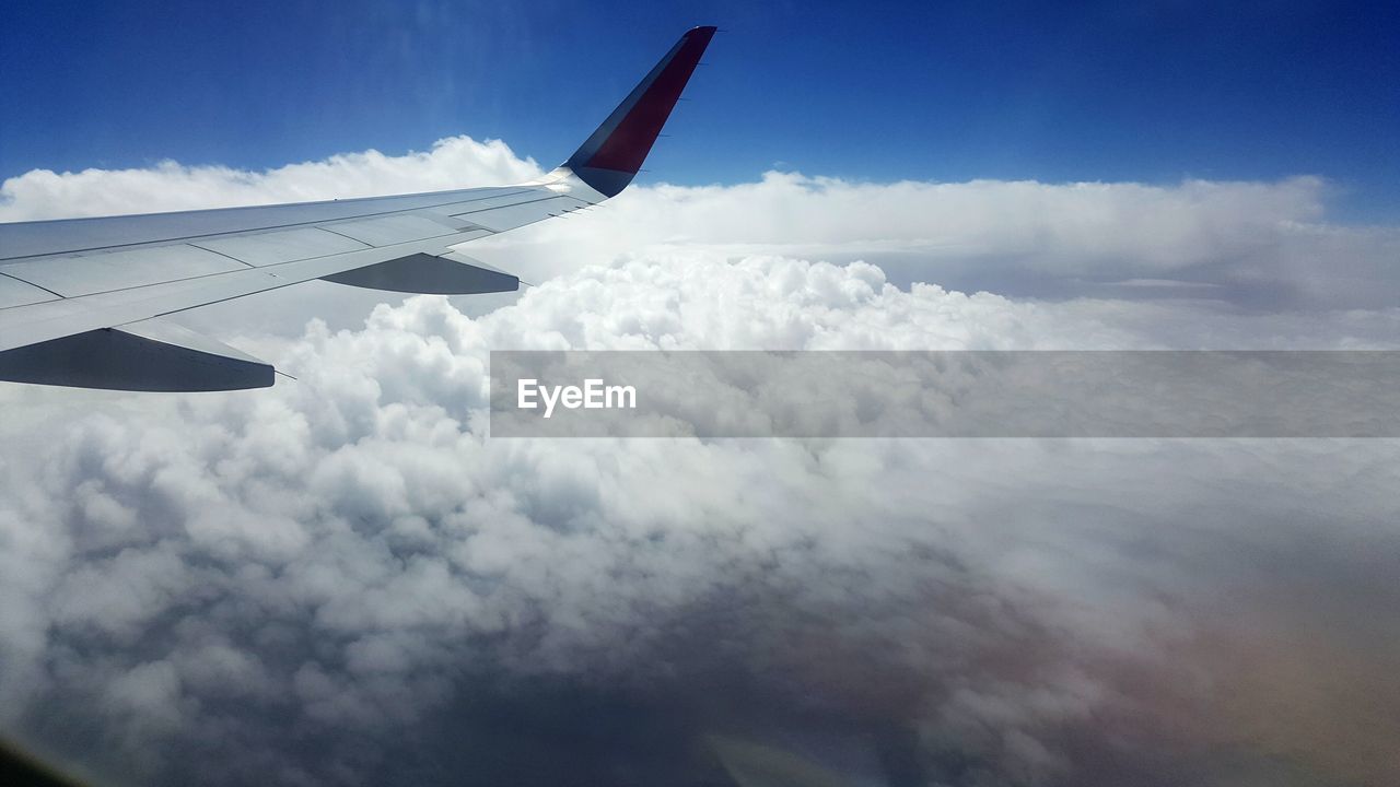 LOW ANGLE VIEW OF AIRPLANE WING OVER CLOUDSCAPE