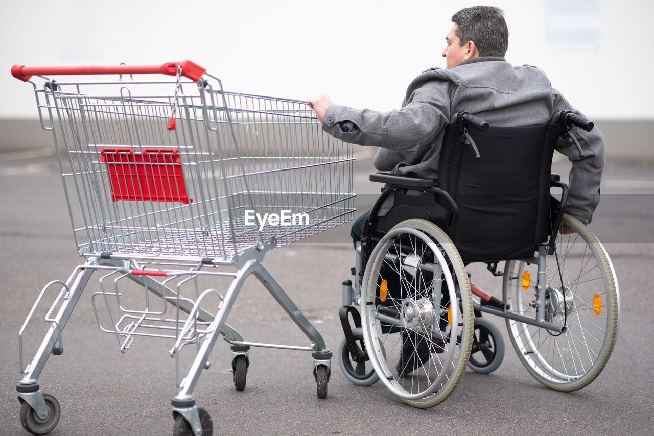 Physical disabled person in a wheelchair pushing shopping cart