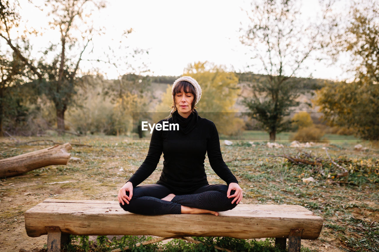 Woman practicing yoga and meditating on the park bench