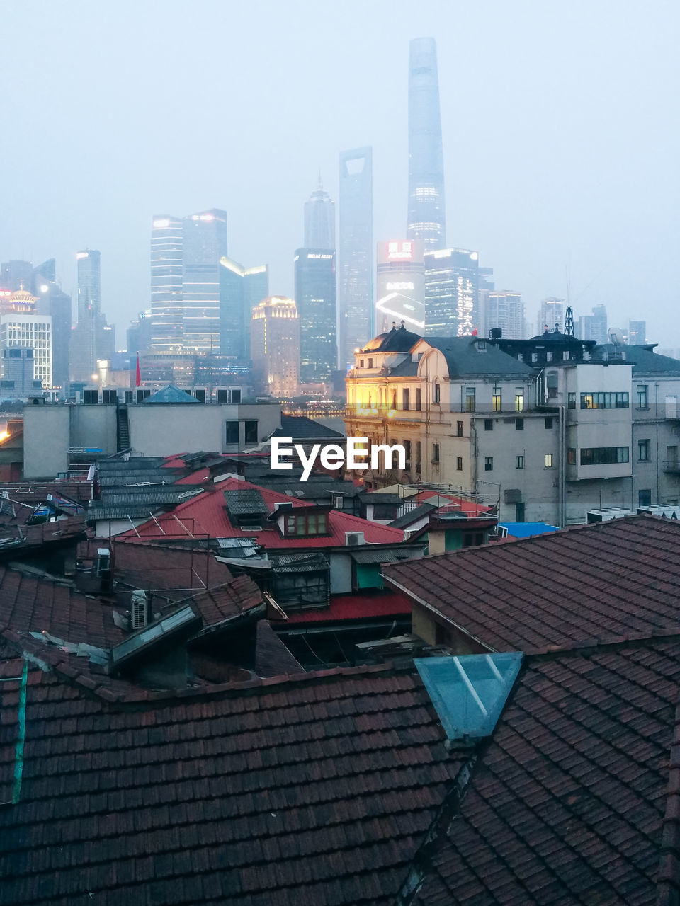 Illuminated buildings against sky in city during foggy weather