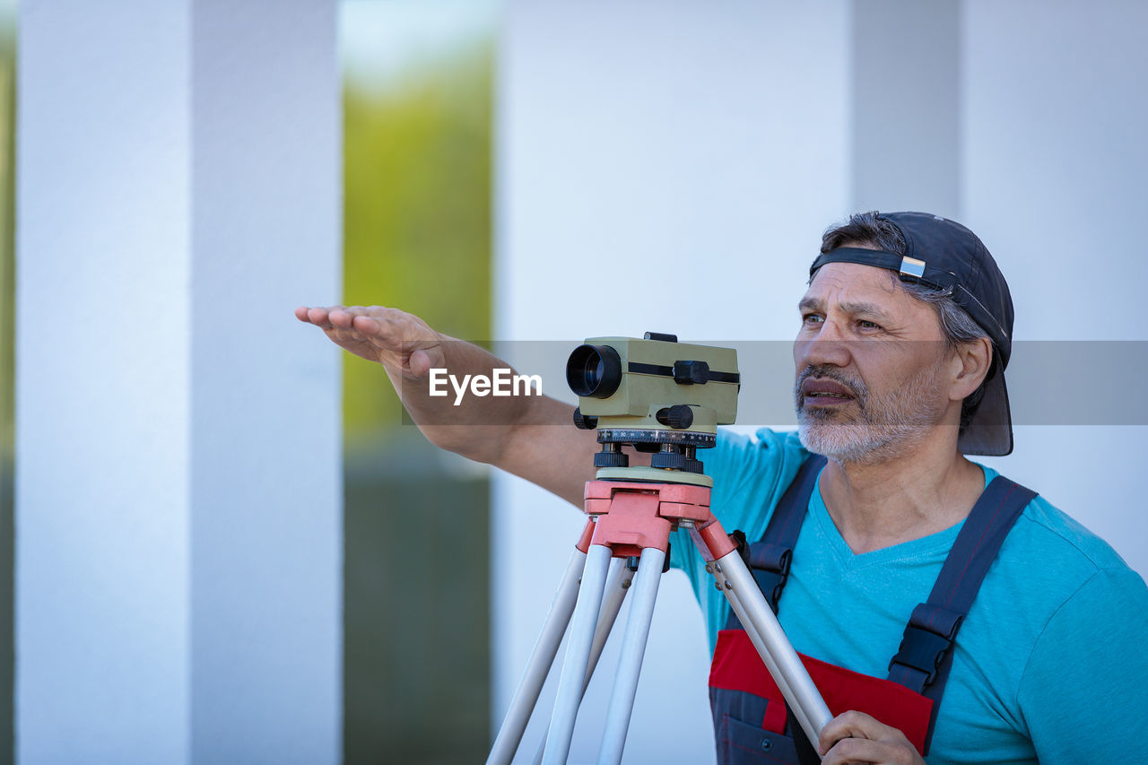 A man works with an optical level to level the landscape.