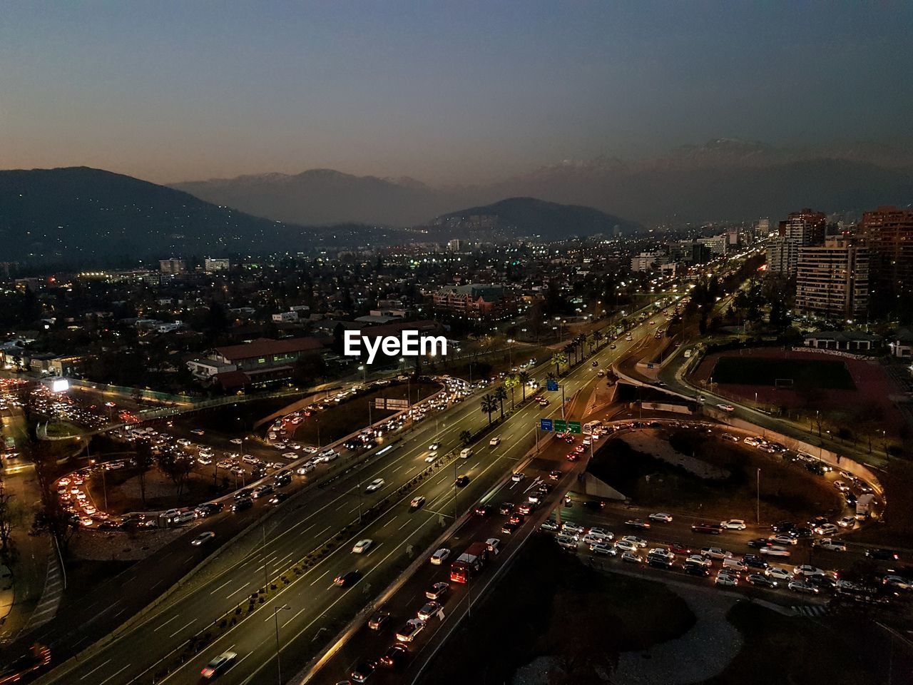 HIGH ANGLE VIEW OF ILLUMINATED CITYSCAPE AGAINST SKY