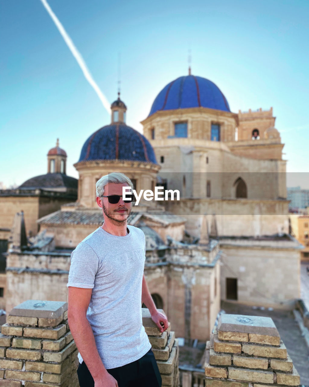 Man standing outside a temple with a beautiful sky