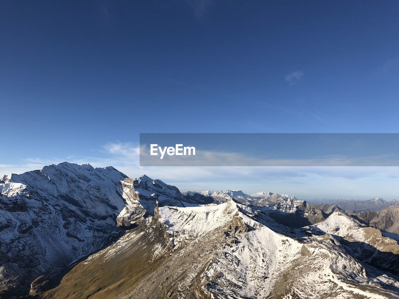 Scenic view of snowcapped mountains against blue sky