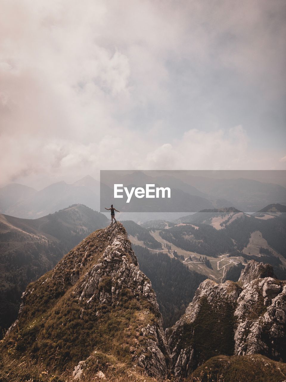 Woman standing on mountain peak against sky