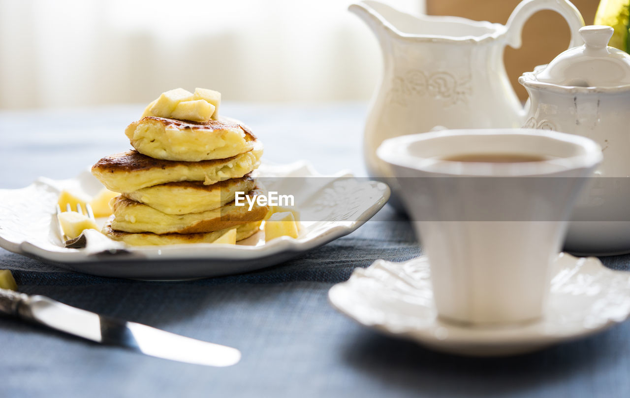 Close-up of apple pancake with tea served on table