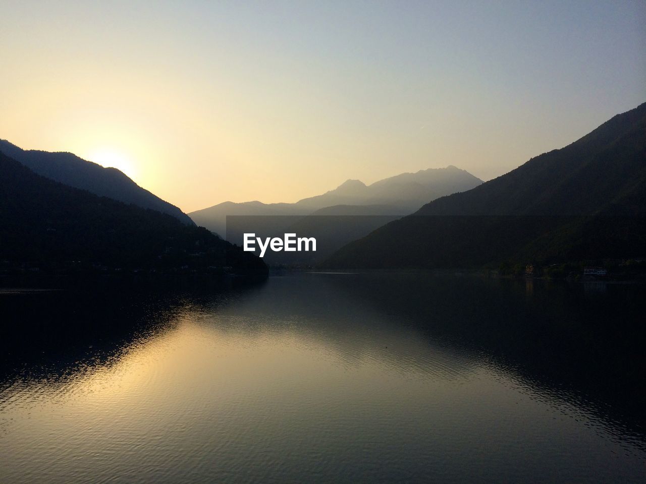 Calm lake against silhouette mountain range