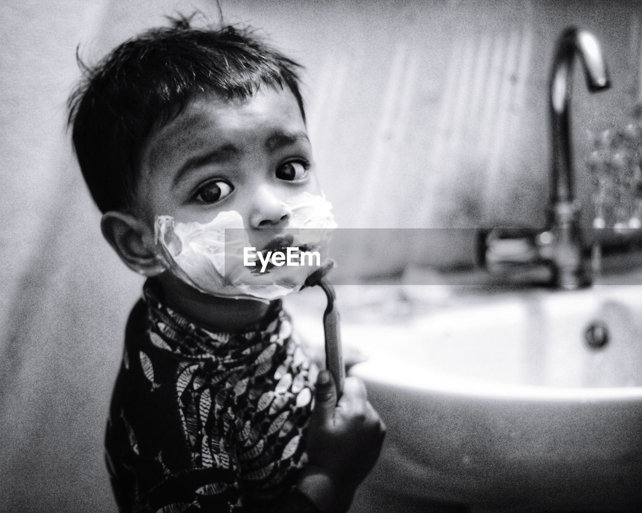 Portrait of cute baby boy shaving in bathroom 