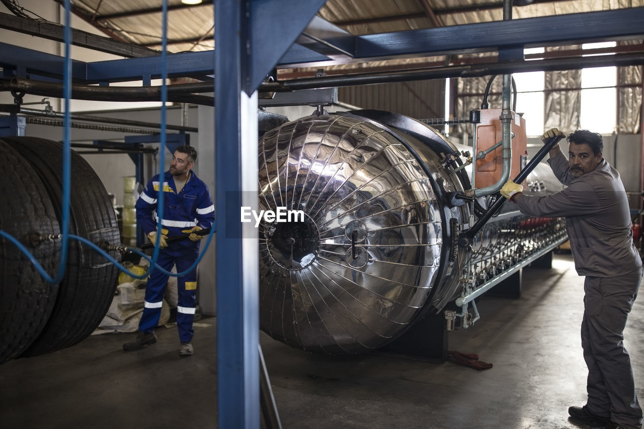 Tire repairmen working on machine in factory