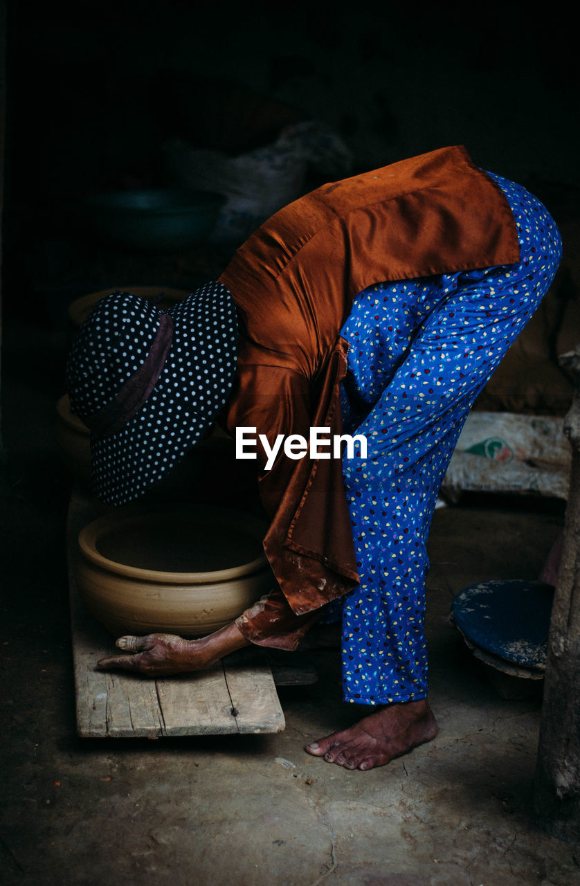 Side view of woman picking container at home