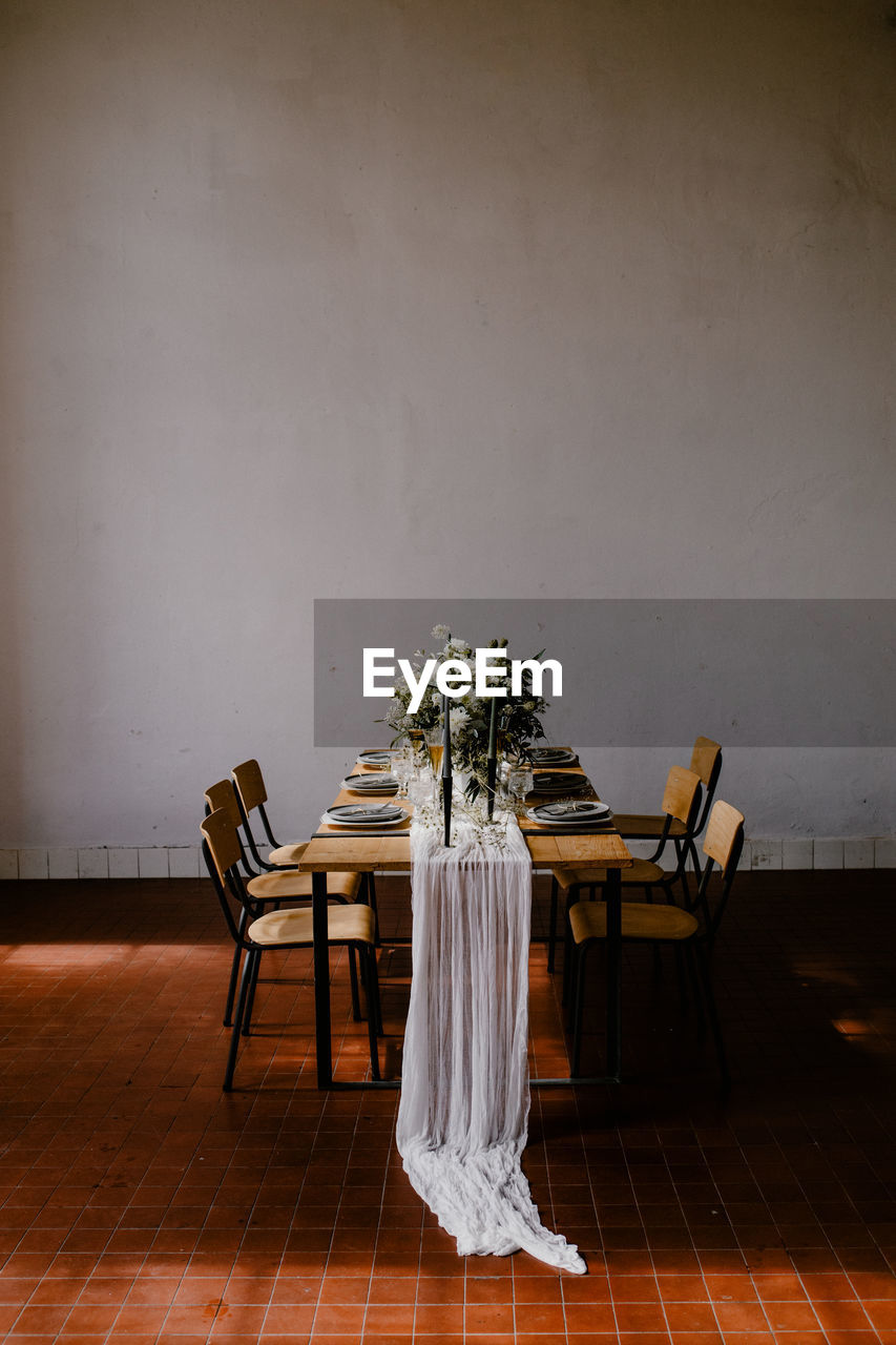 EMPTY CHAIRS AND TABLE AGAINST WALL