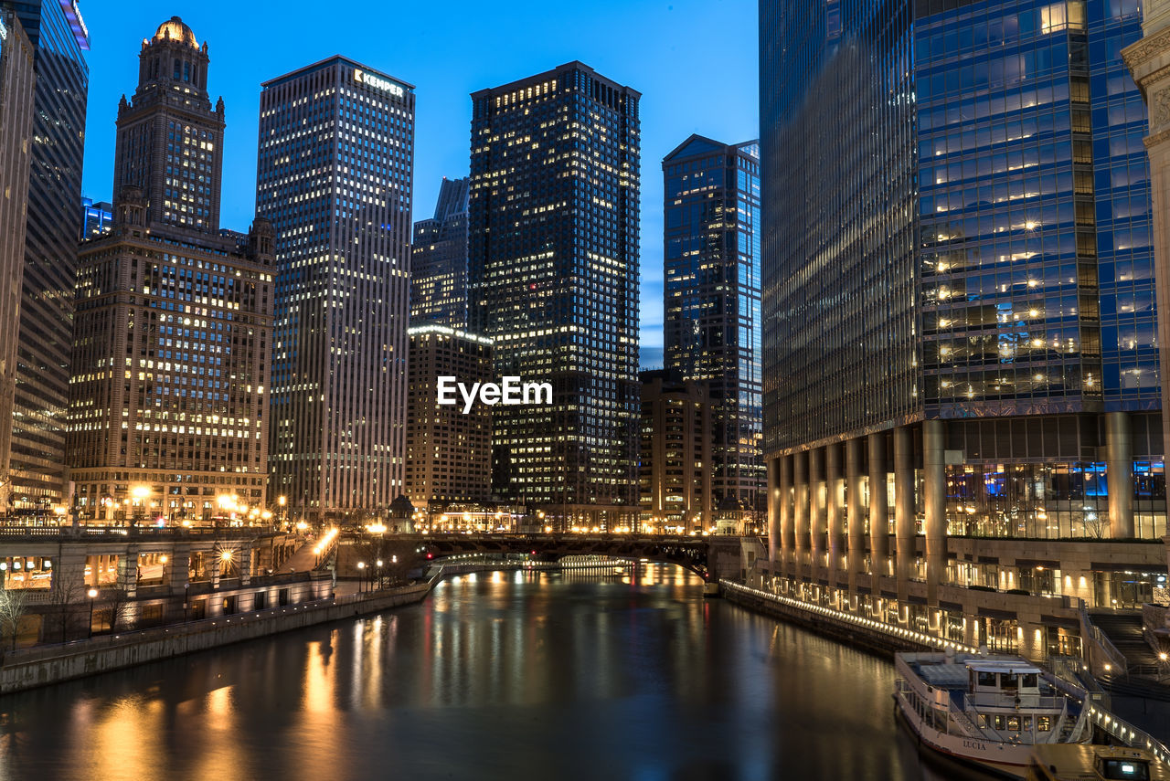 Illuminated buildings by river at night