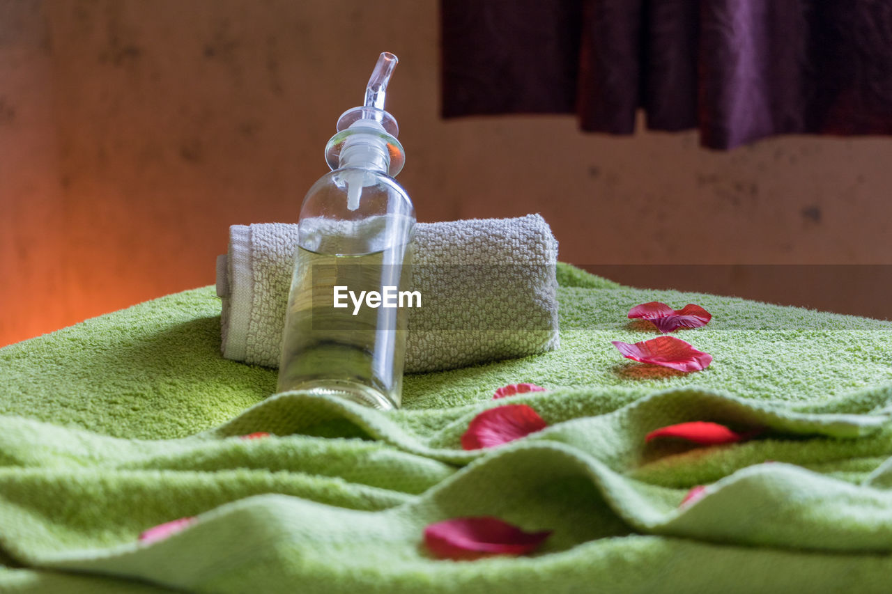 Close-up of spray bottle with towel on bed