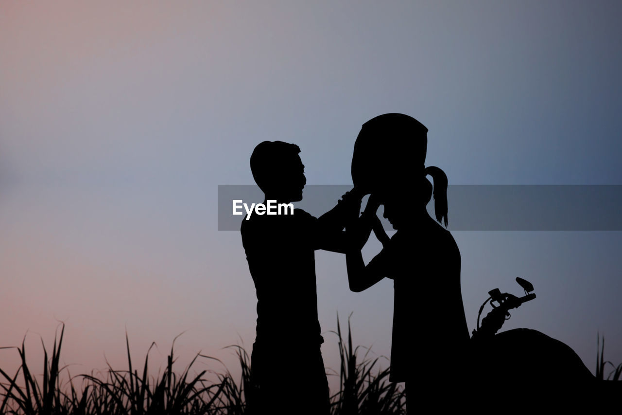 Silhouette couple standing against sky during sunset