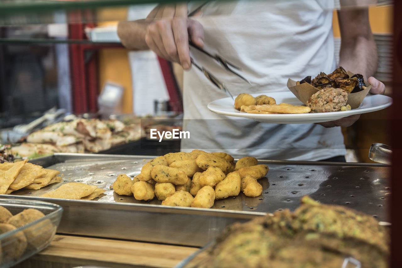 Midsection of man taking food in plate