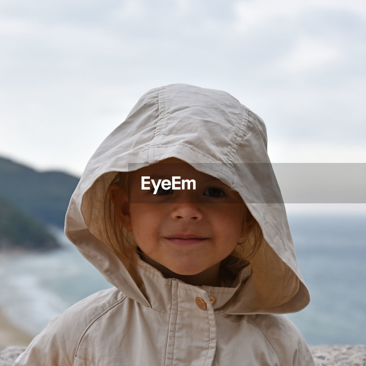 Portrait of cute smiling girl against sea and sky